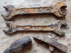 three old rusty wrenches are laying on a piece of wood that has been chipped off