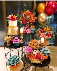 a table topped with cakes and cupcakes covered in frosting next to balloons