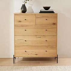 a wooden dresser with two vases on top of it and a rug in front of it