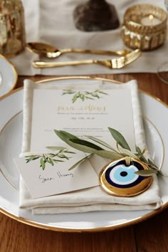 the table is set with gold and white plates, napkins, and place settings