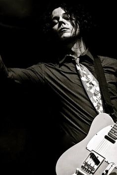 black and white photograph of a man playing an electric guitar with his hands in the air