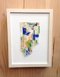 a white frame holding a colorful piece of art on a wooden wall with wood planks