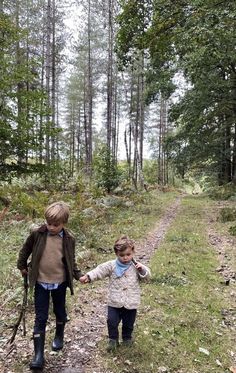 two children walking in the woods holding hands