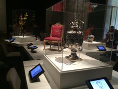 several electronic devices are on display in glass cases with chairs and vases behind them