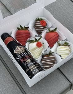 a box filled with chocolate covered strawberries next to a bottle of wine on top of a table