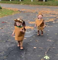 two young children dressed in costumes walking down the street