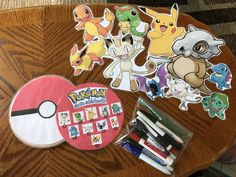 some pokemon stickers and markers are on a wooden table with other items around it