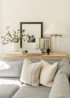 a living room with a gray couch and white pillows on it's side table