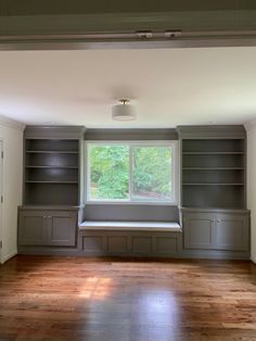 an empty room with built in bookshelves and wooden floors