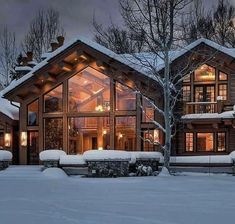 a large house with lots of windows and lights on it's side in the snow