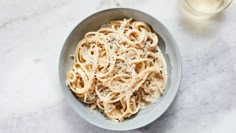 a bowl filled with pasta next to a glass of wine