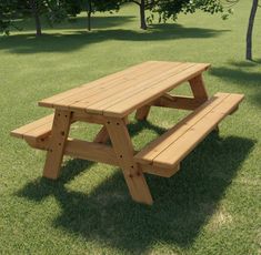 a wooden picnic table sitting on top of a lush green grass covered park field with trees in the background