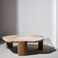 a marble coffee table sitting on top of a cement floor next to a white wall