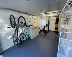 there is a bike hanging on the wall in this garage with other bikes and equipment