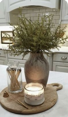 a candle sits on a cutting board next to a vase with some flowers in it