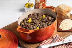 a pot full of food sitting on top of a wooden cutting board next to bread