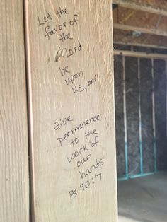 graffiti written on the side of a wooden wall in an unfinished room with metal bars