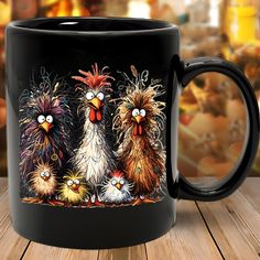 a black coffee mug with three different colored chickens on the front and sides, sitting on a wooden table