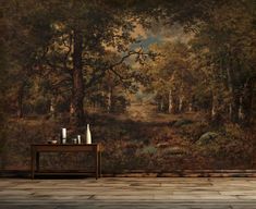 an empty table in front of a wall with a painting on it that looks like a forest