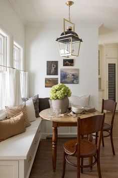 a dining room table with chairs and a bench in front of the window that has pictures on it