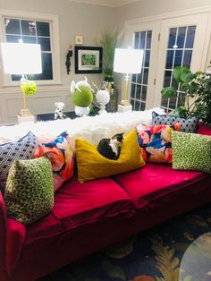 a living room filled with lots of furniture and pillows on top of a red couch