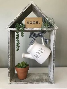 a house shaped shelf with a watering can and potted plant