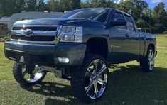 a black truck parked on top of a lush green field