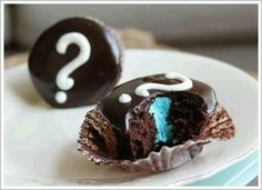 two chocolate desserts on a white plate with question mark in the middle and one has blue frosting