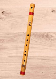 a wooden flute with chinese writing on it sitting on top of a wood floor next to a wall