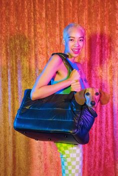 a woman holding a blue purse with a dog in it