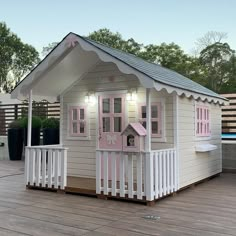 a small wooden house with pink windows and white picket fence around the front porch area