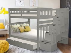 a gray bunk bed with stairs next to a white couch and yellow pillows on the floor