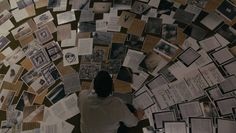 a person standing in front of a wall covered with lots of papers and pictures on it