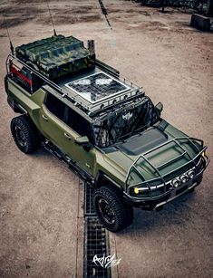 an army truck parked in the middle of a parking lot with its hood up and luggage on top