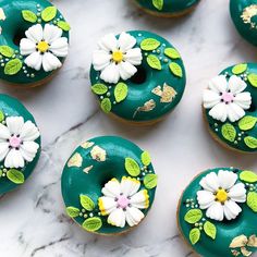 green donuts decorated with flowers and leaves on a marble countertop, ready to be eaten