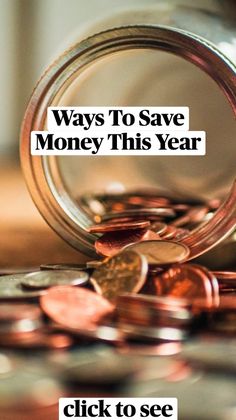 a jar filled with coins sitting on top of a wooden table next to a pile of pennets