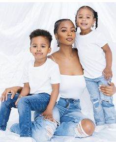 a woman and two children sitting on top of each other in front of a white backdrop