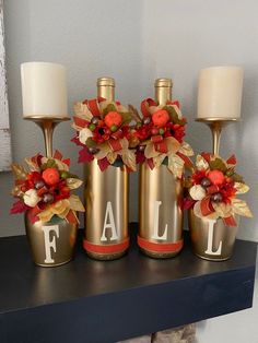 three gold vases with flowers and candles on a mantle