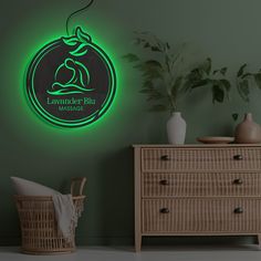 there is a green neon sign on the wall next to a dresser and potted plant