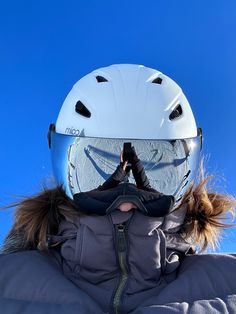 a person wearing a snowboard helmet while standing in front of a blue cloudless sky