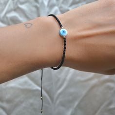 Pulsera de hilo chino con ojo de perla madre y chaquiras negras.