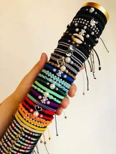 a hand holding a stack of bracelets with lots of beads and pearls on them