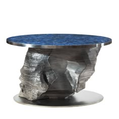 a round table with a blue top and silver base on a metal plate, against a white background