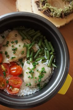 a bowl filled with rice and vegetables on top of a wooden table