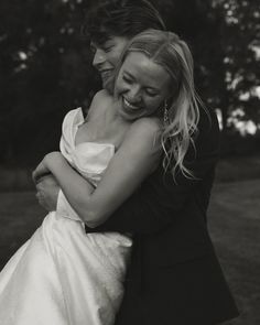 black and white photograph of two brides hugging each other in front of some trees