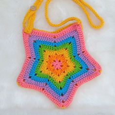 a multicolored crocheted bag sitting on top of a white furnishing