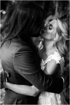 black and white photograph of two women kissing each other in front of a christmas tree