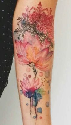 a woman's arm with watercolor flowers and dots on the bottom of it