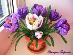 a vase filled with purple flowers sitting on top of a table next to a window