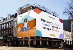 a large advertisement on the side of a building with a woman sitting on an orange couch